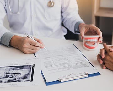 Dentist holding paperwork and smile model