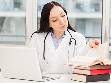 Doctor looking at books and laptop