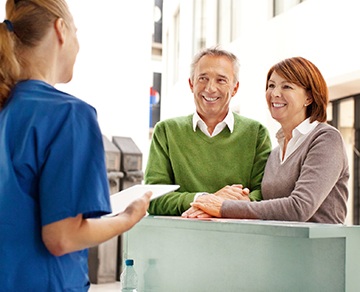 Smiling man and woman at dental reception desk